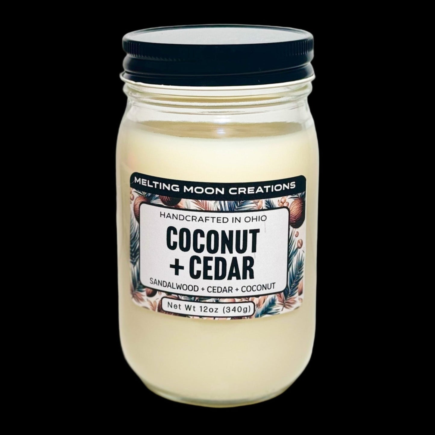 Coconut + Cedar candle in glass jar with black twist on lid sitting on white backdrop. Candle label designed by Melting Moon Creations.
