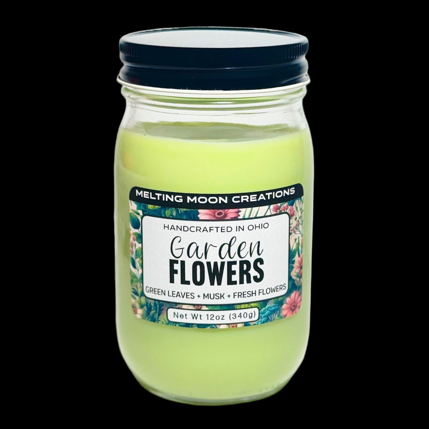 Garden Flowers candle in glass jar with black twist on lid. Sitting on white backdrop. Label designed by Melting Moon Creations.