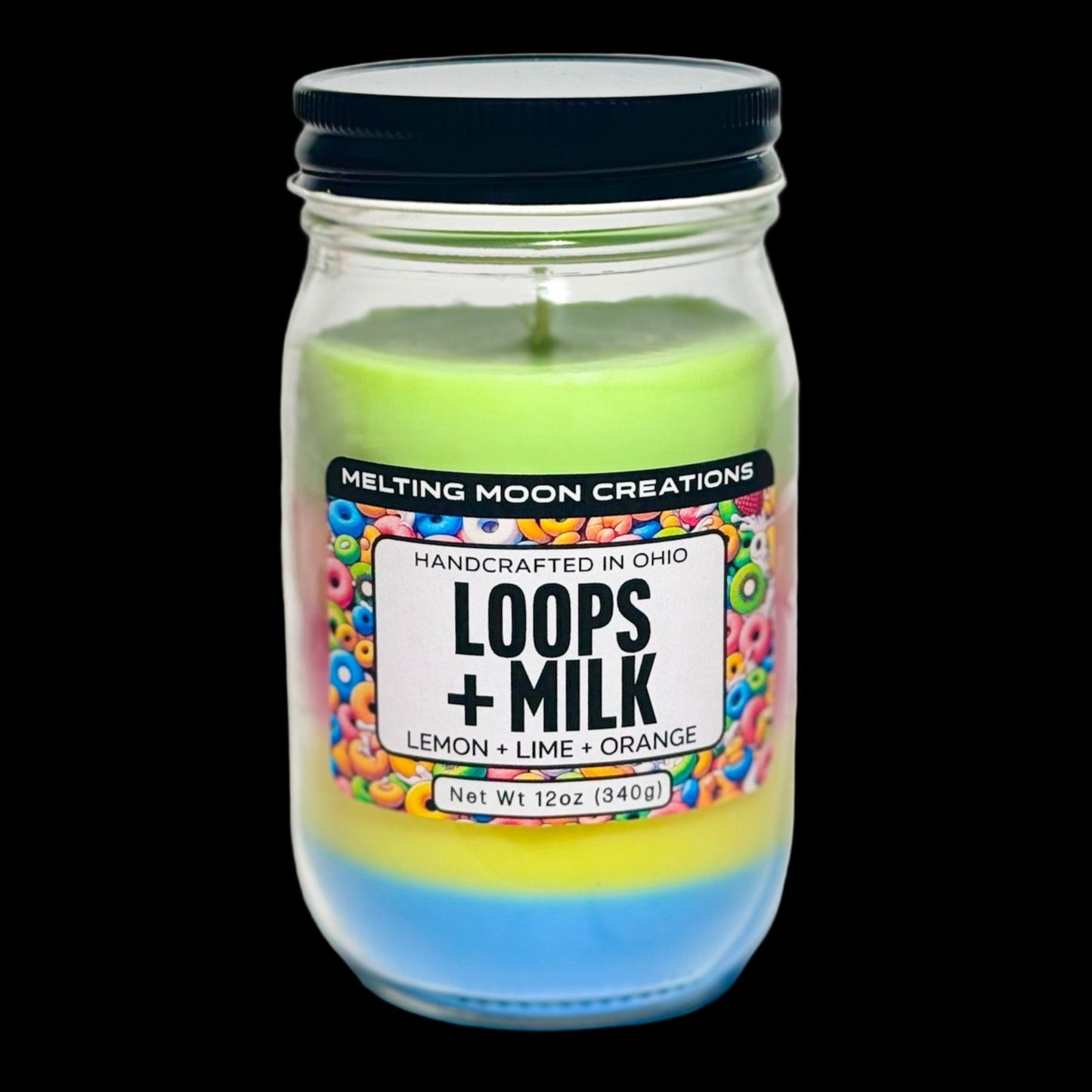 Loops + Milk candle in a glass jar with black twist on lid sitting on a white backdrop. Candle wax is dyed in even layers of rainbow colors. Candle label designed by Melting Moon Creations.