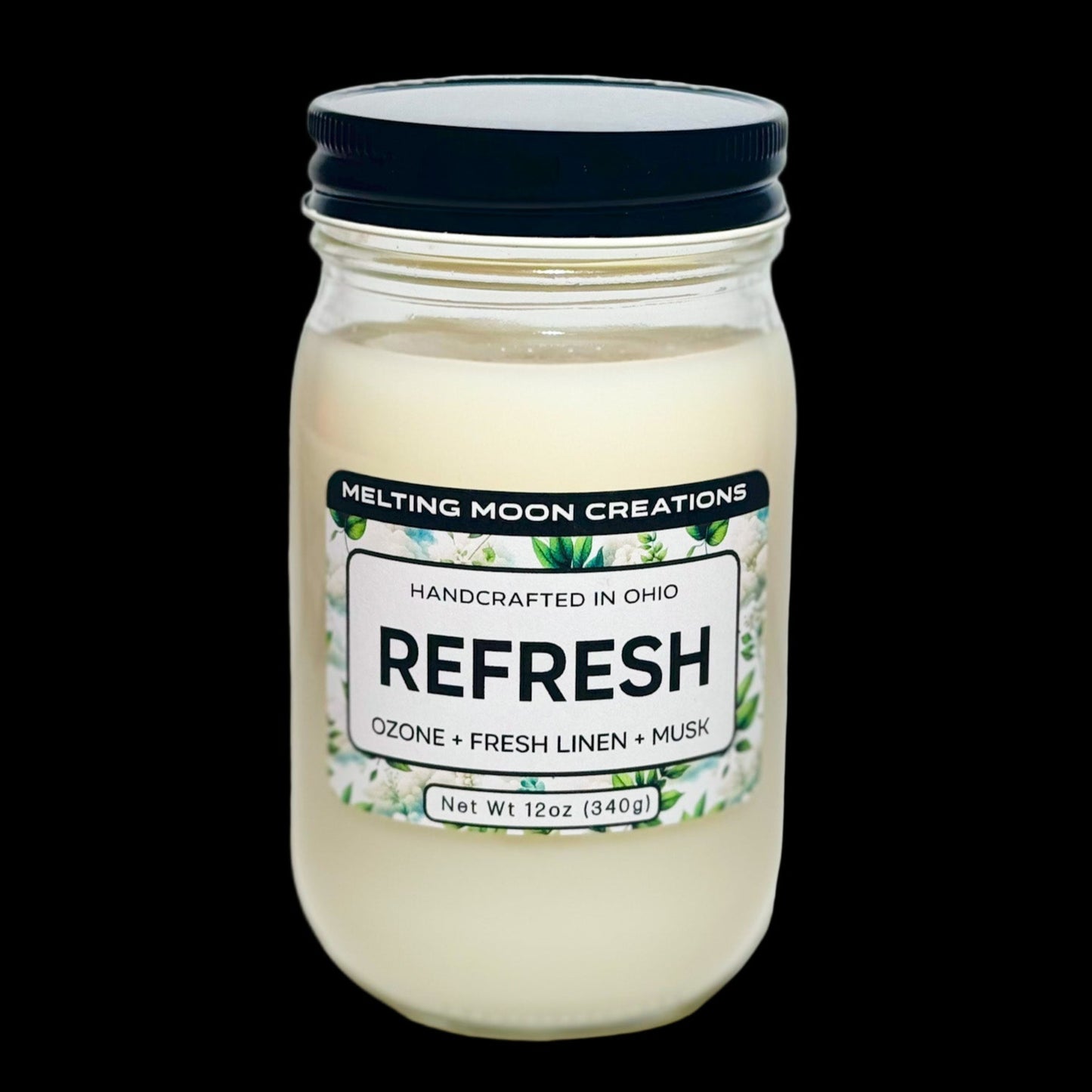 Refresh candle in glass jar with black screw on lid sitting on white backdrop. Candle label designed by Melting Moon Creations.