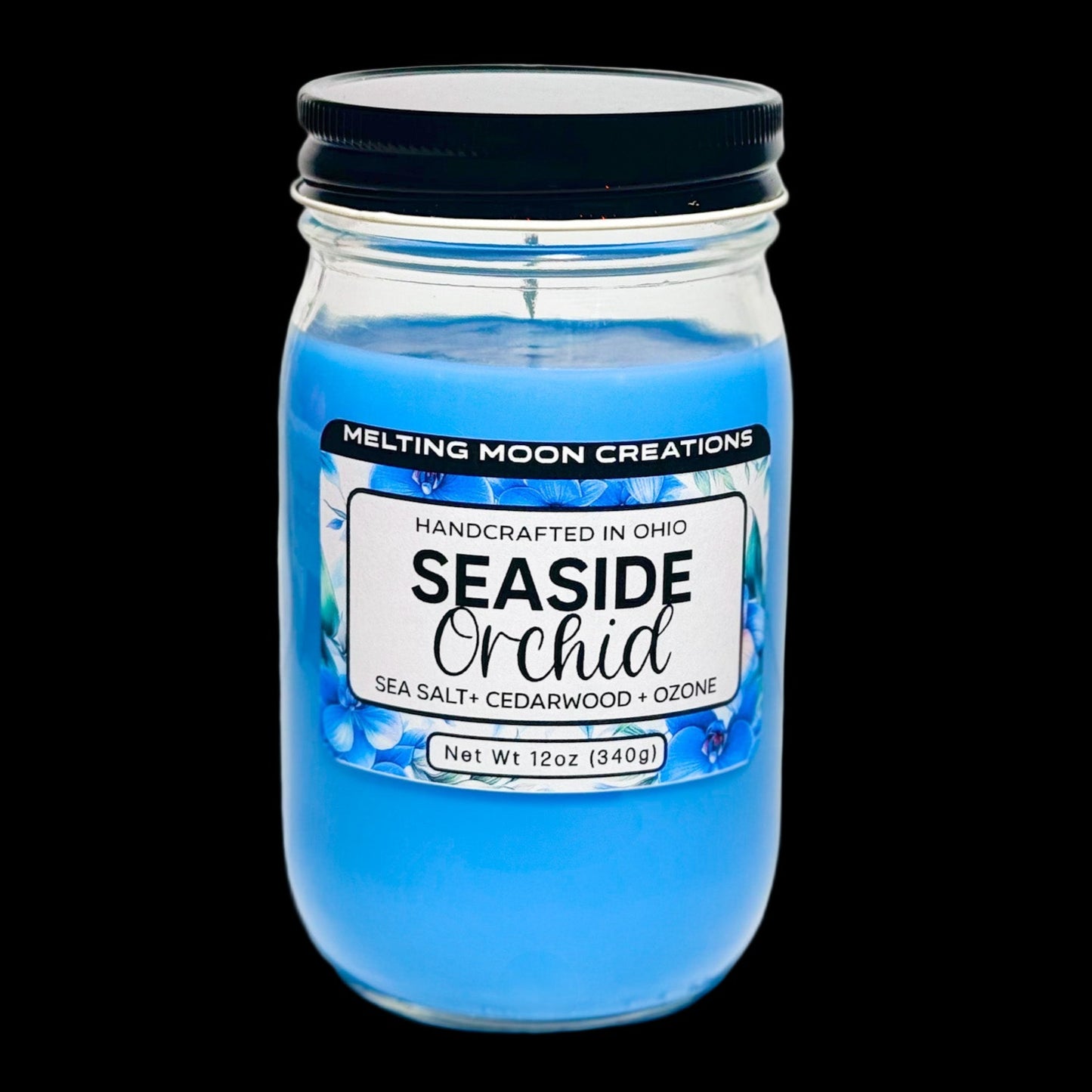 Seaside Orchid candle in glass jar with black twist on lid sitting on a white backdrop. Label designed by Melting Moon Creations.