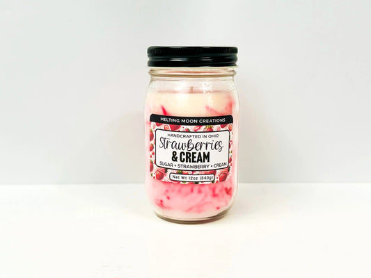 Strawberries and Cream candle in glass jar with back twist on lid sitting on white backdrop. Pink and white marbled wax. Label created by Melting Moon.