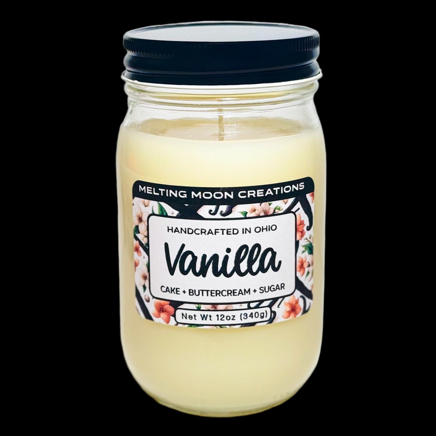 Cream white Vanilla scented candle in a glass jar with black screw on lid. Sitting on white backdrop. Label designed by Melting Moon Creations.
